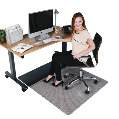 A woman sits at a desk with a computer, using an Aleco Sit or Stand Mat on the floor, which protects the carpet.