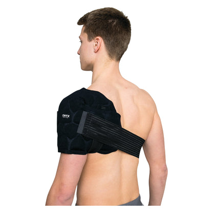 A person wears the Xena Therapies Onyx Cool Shoulder+ on their left shoulder, with black straps securing it in place.