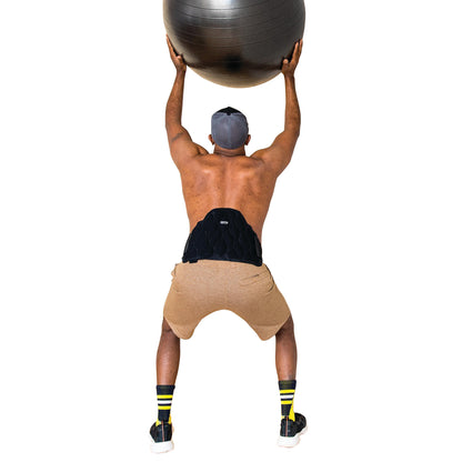 A man squats holding a stability ball overhead, wearing the Xena Therapies Onyx Cool Back/Hip support.