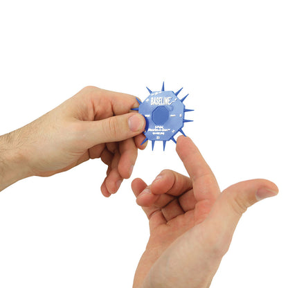 Two hands hold a blue Baseline DISCRIM-A-GON, a sensory measurement tool with protruding spikes and measurement markings.