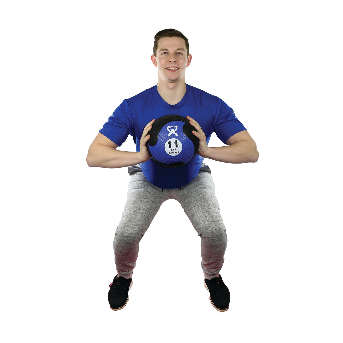 A person in a blue shirt squats, holding a CanDo Rubber Medicine Ball. The ball is blue and marked with "4.9 kg" and "11 lbs."