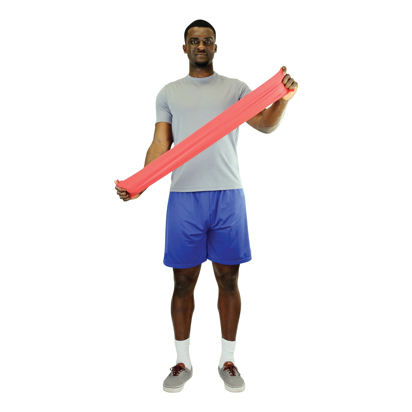 A person stretches a red CanDo Non-Latex Exercise Band. They wear a gray shirt, blue shorts, and sneakers.