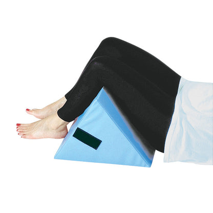 Person's legs rest on a blue foam wedge. This is the AliMed Knee Bolster and Extension Set, designed for knee support.