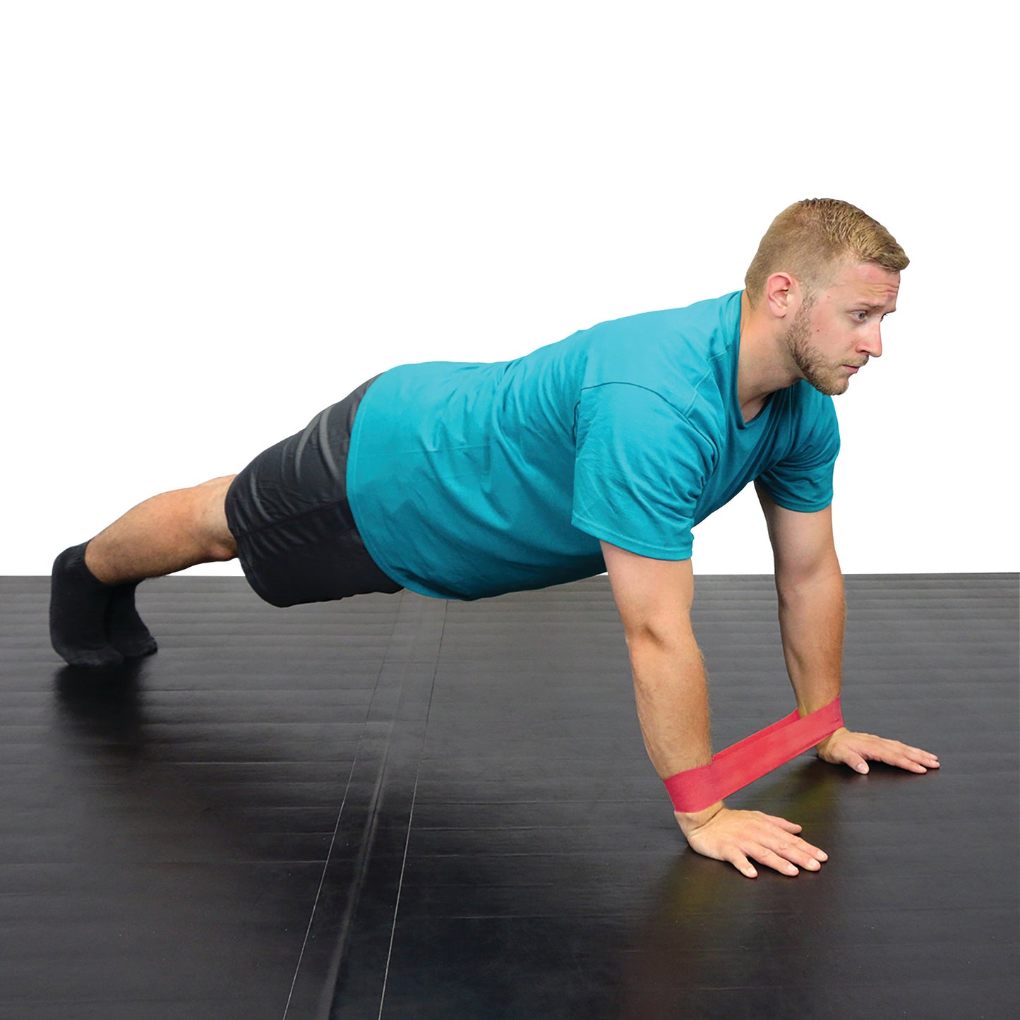 A person performs a plank on a black mat using a red CanDo Band Exercise Loop around their wrists for resistance.