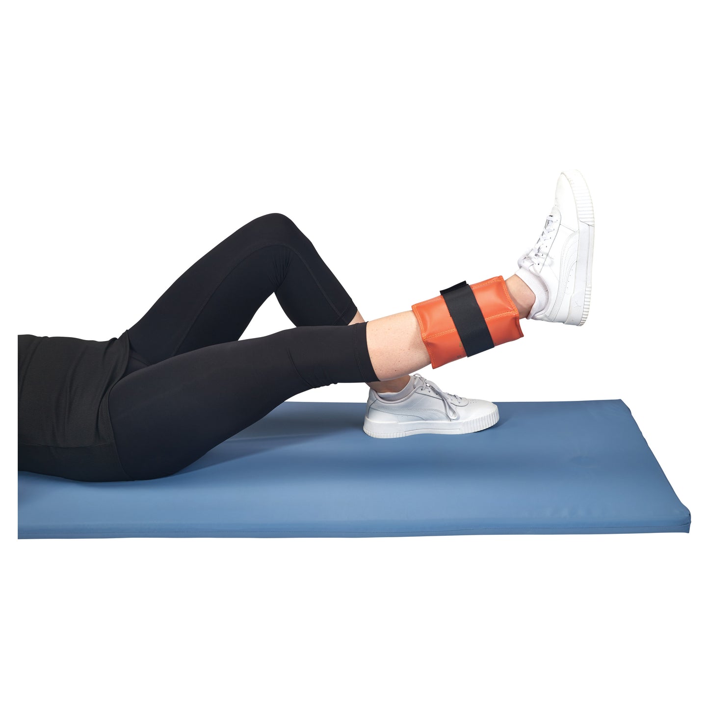A person lying on a blue mat wears an AliMed Color-Coded Cuff Weight on their ankle, with one leg bent and wearing white sneakers.