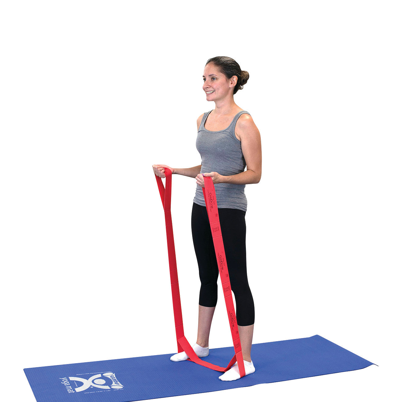 A woman uses a CanDo Multi-Grip Exerciser, a red resistance band, while standing on a blue exercise mat.