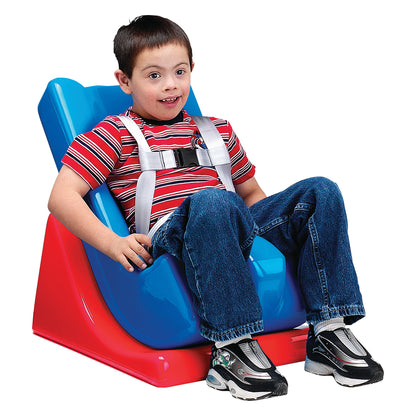 A child sits in a Tumble Forms2 Deluxe Feeder Seat System, which is blue with a red base and features a harness for support.