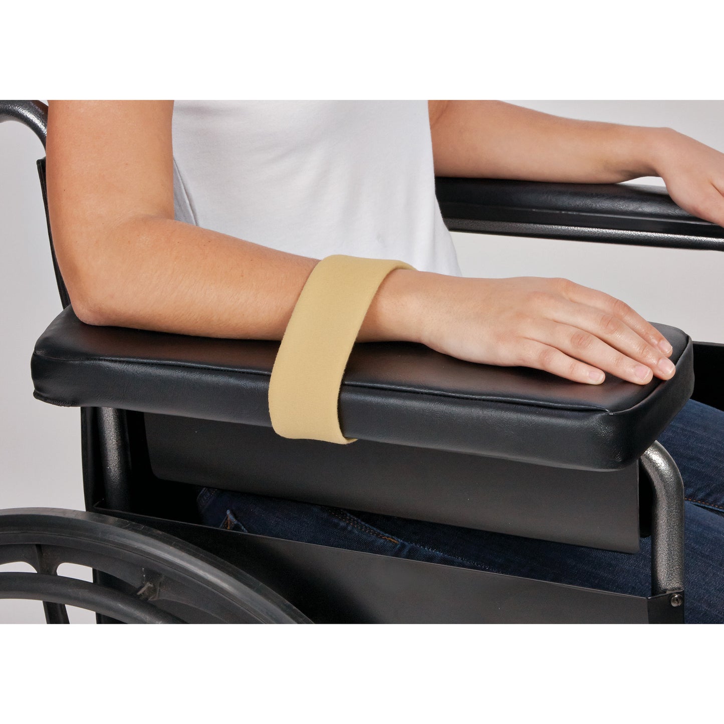 A person uses an AliMed Beta Pile II Loop to secure their arm on a wheelchair's black armrest.