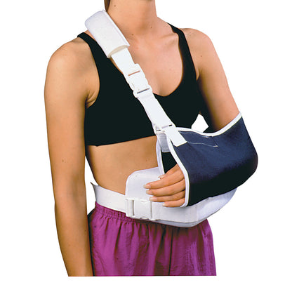 A person wears a Shoulder Immobilizer with Contoured Arm Wedge and Body Strap, featuring a padded shoulder and arm support.
