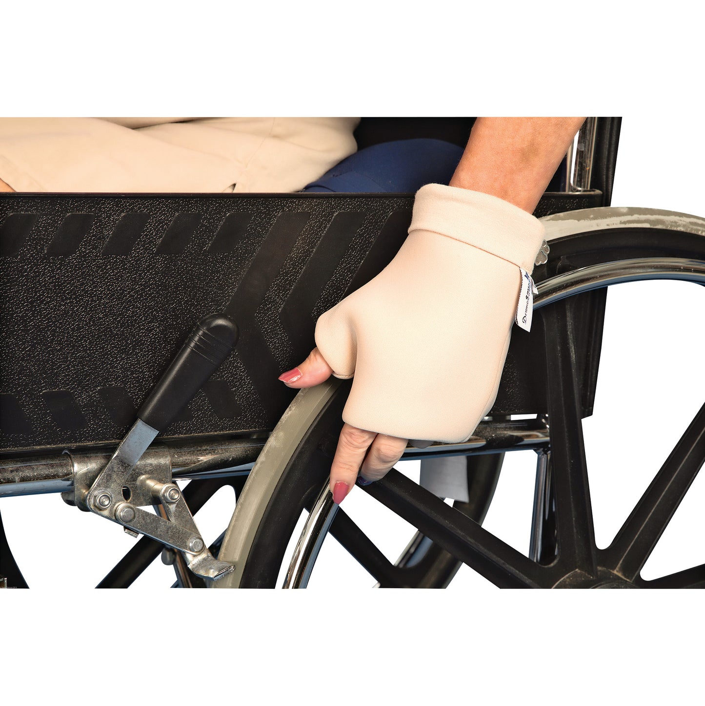 A hand wearing a DermaSaver Knuckle Protector holds the wheel of a wheelchair, with a grip lever visible beside the wheel.