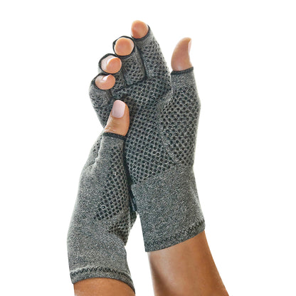 Hands wearing Brownmed IMAK Compression Arthritis Gloves, featuring a grey fabric with a textured pattern and open fingertips.