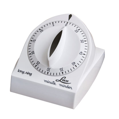 A white Lux minute minder bell timer with a black dial marked from 0 to 60 minutes, labeled "long ring" and "Lux minute minder."