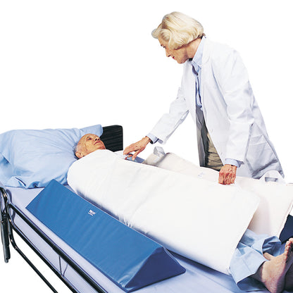 A caregiver adjusts a person in bed using the SkiL-Care In-Bed Patient Positioning System, featuring blue triangular supports.