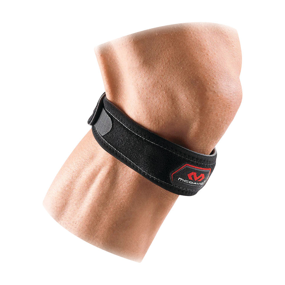A forearm wearing a McDavid Jumper's Knee Strap, black with a red logo, designed for support and pain relief.