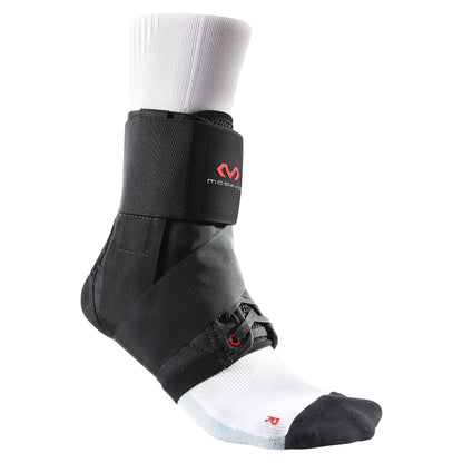 A McDavid Ultralight Ankle Brace is shown on a foot wearing a black and white sock. The brace has cross straps and black material.