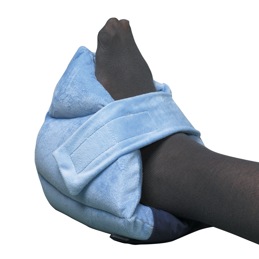A SkiL-Care Gel-Foam Heel Cushion in light blue wraps around a foot wearing a dark sock, secured with a strap.