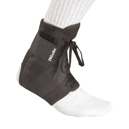 A foot wearing the Mueller Soft Ankle Brace with Straps over a white sock. The brace is black and laced up for support.