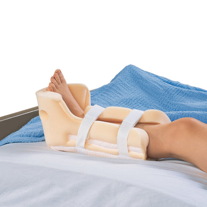 A person wearing a HEELIFT Traction Boot with foam padding and straps, lying on a bed with a blue blanket.
