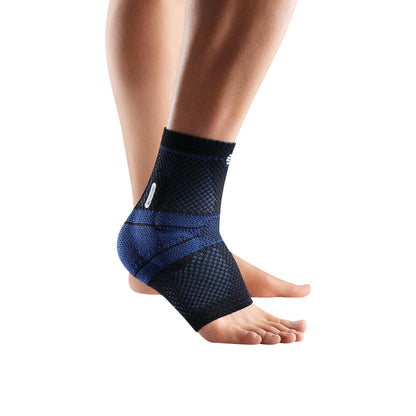 Person wearing a Bauerfeind MalleoTrain Ankle Support. The black and blue brace is fitted around the ankle for support.