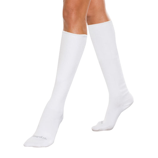A person wearing SmartKnit Seamless Over-the-Calf Socks in white, extending up to just below the knees on a plain background.