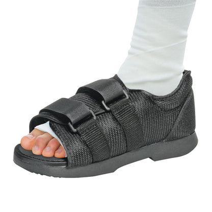 A foot wearing the AliMed Pediatric Classic Post-Op Shoe with adjustable straps. The shoe is black with an open toe design.