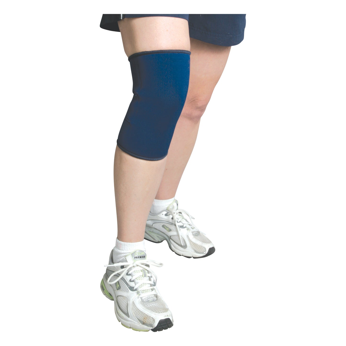 Person wearing AliMed Knee Support with Closed Patella. The knee support is blue, and the person is wearing white sneakers.