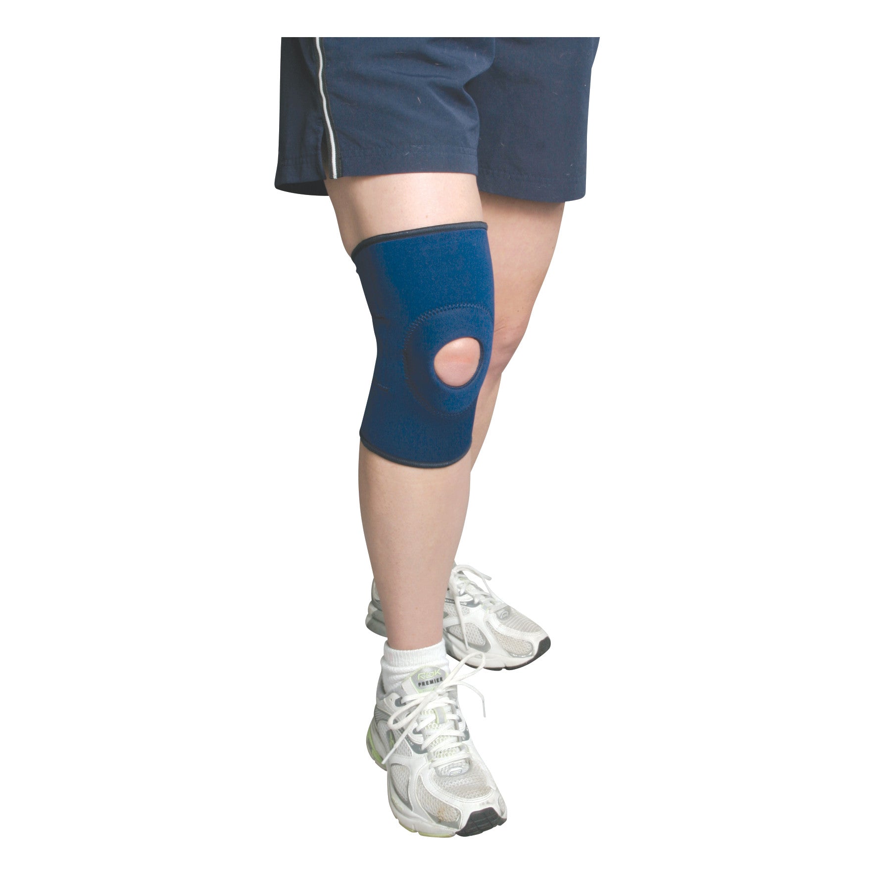 Person wearing the AliMed Knee Support with Open Patella. White sneakers and dark shorts are also visible.