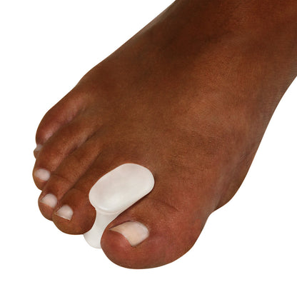 A foot wearing a Silipos Gel Toe Spreader, positioned between the big and second toes to provide separation and cushioning.