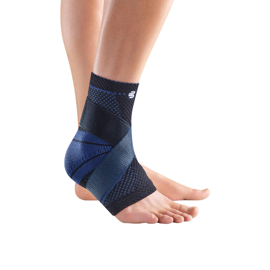 A person wears a Bauerfeind MalleoTrain S Ankle Support, featuring blue and black elastic material wrapping around the ankle.