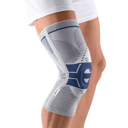 Person wearing a Bauerfeind GenuTrain P3 knee brace, featuring a gray and blue design, providing support to the knee joint.