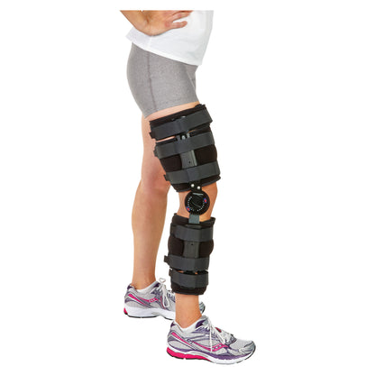 A person wears the AliMed FREEDOM Comfort Post-Op Knee Brace with ROM Fast Set Hinge over shorts and athletic shoes.