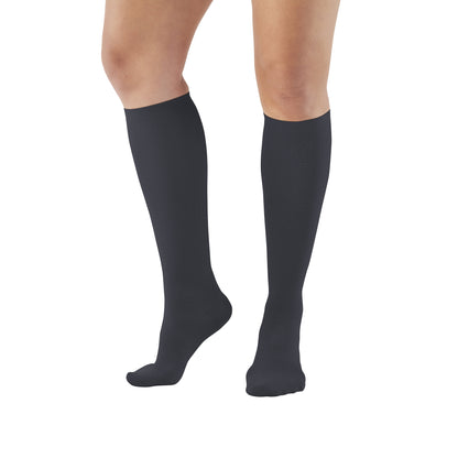 A person wears Ames Walker Knee-Length Microfiber Support Socks. They are dark-colored and reach just below the knees.