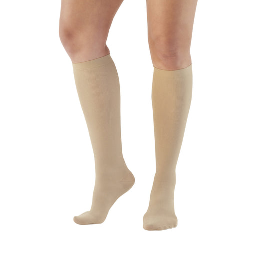 A person wears beige Ames Walker Knee-Length Microfiber Support Socks on both legs, showcasing the fit and design.