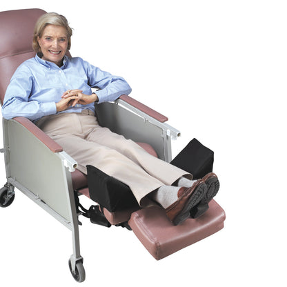 A person sits comfortably in a reclined chair using the SkiL-Care Geri-Chair Leg Positioner to elevate and support their legs.