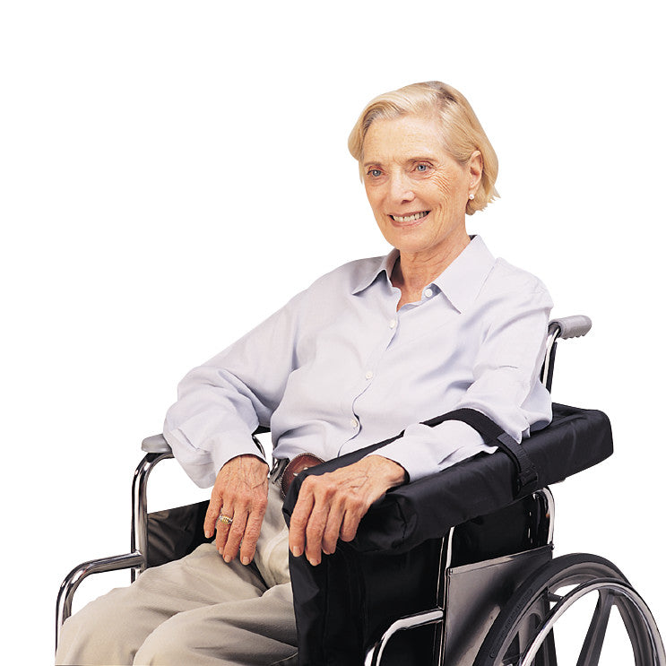 A smiling elderly woman sits in a wheelchair using the SkiL-Care Lateral Arm/Body Support, providing comfort and stability.
