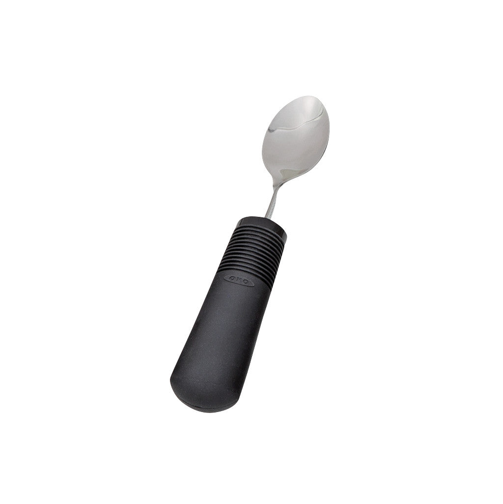 A Good Grips Weighted Utensil spoon with a wide, textured black handle and a shiny metal bowl.