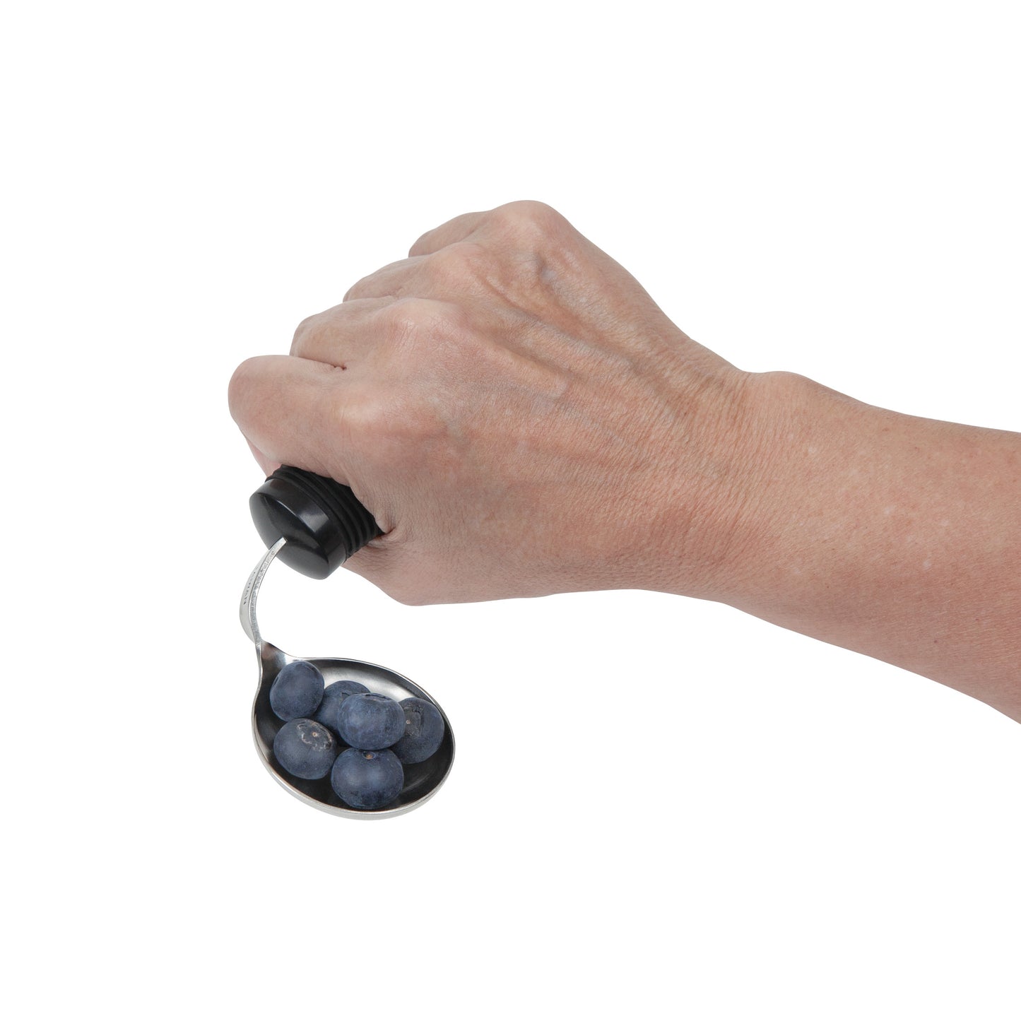 A hand holding a Good Grips Weighted Utensil spoon with blueberries on it. The utensil has a black handle.