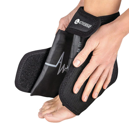 A person adjusts an ActiveWrap foot and ankle therapy wrap on their foot. The wrap is black with a visible brand logo.