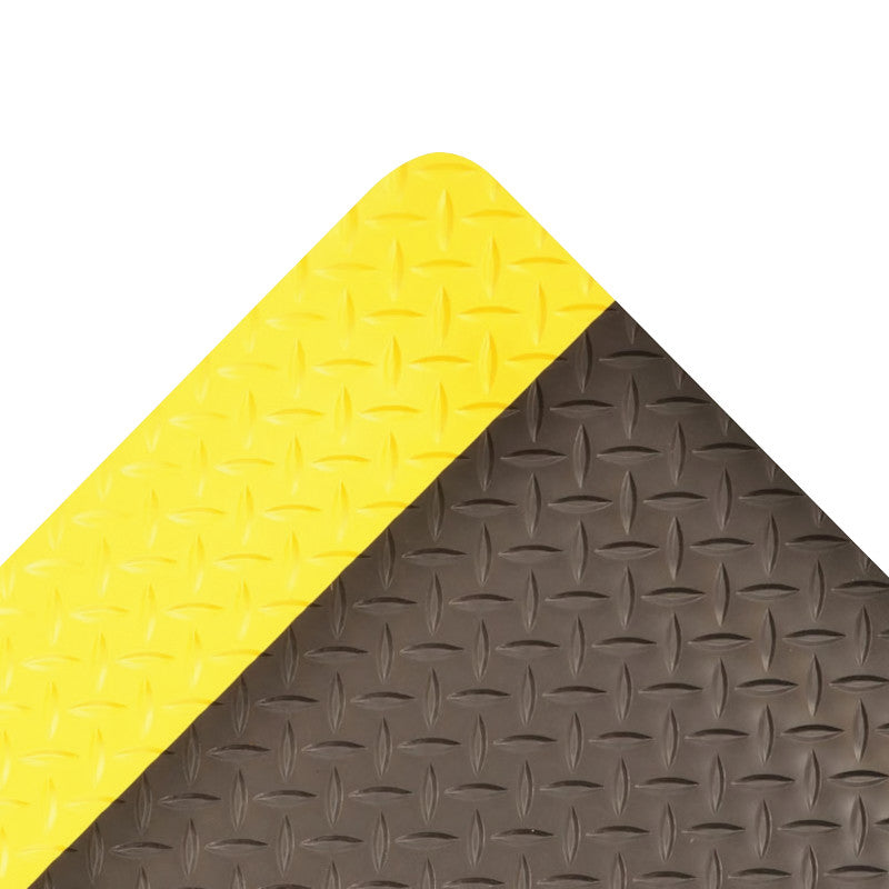 Close-up of a Saddle Trax Anti-Fatigue Mat, featuring a yellow and black diamond plate pattern, with a corner shown.