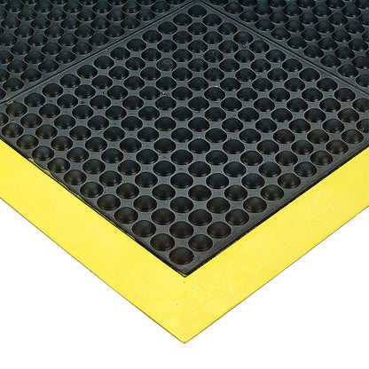 Close-up of a Wearwell Ortho Stand Anti-Fatigue Mat with black textured surface and yellow beveled edges.