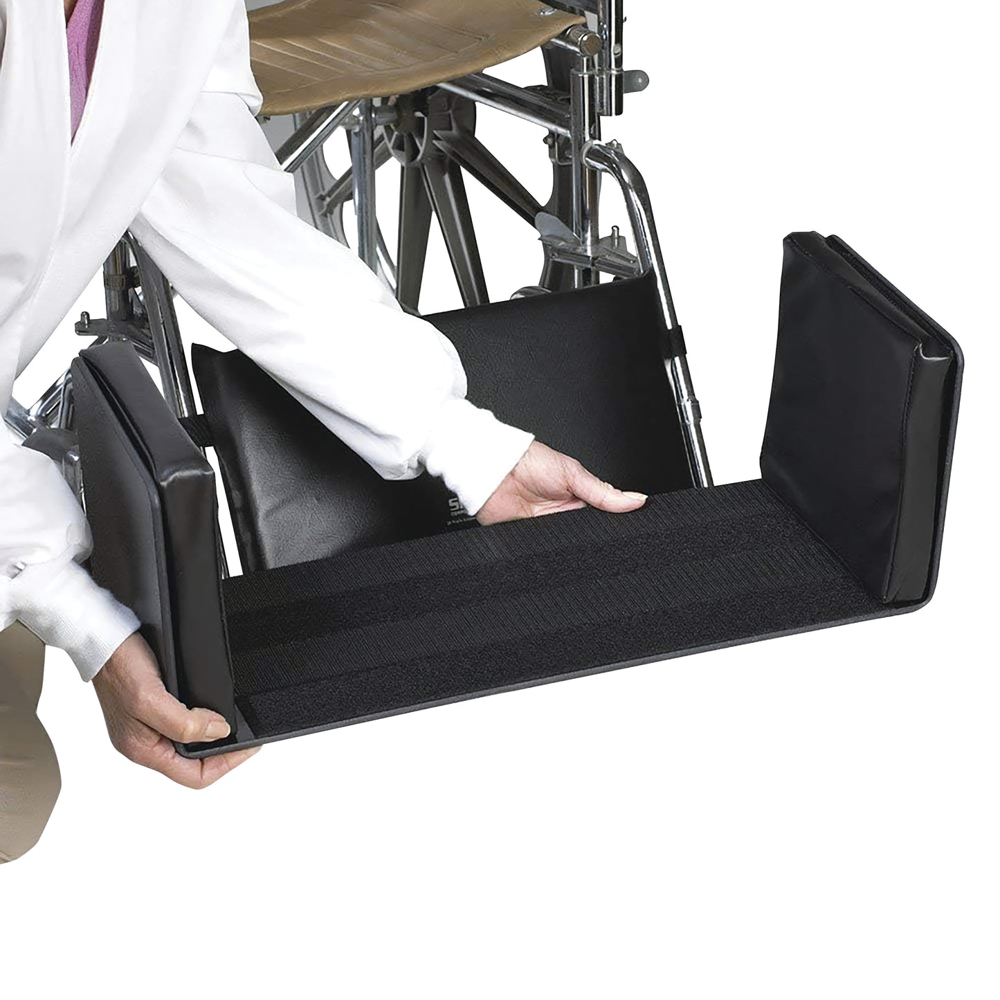 A person holds a SkiL-Care Side-Kick Pad, a black padded accessory used with wheelchairs for added comfort and support.