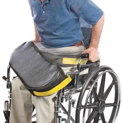A person in a wheelchair using the AliMed BreakAway Lap Cushion with Basic Alarm, featuring a black cushion and yellow handles.