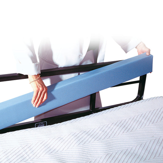 A person places the AliMed Bed Stuffer Safety Bolster on a metal bed rail, with a quilted mattress visible below.