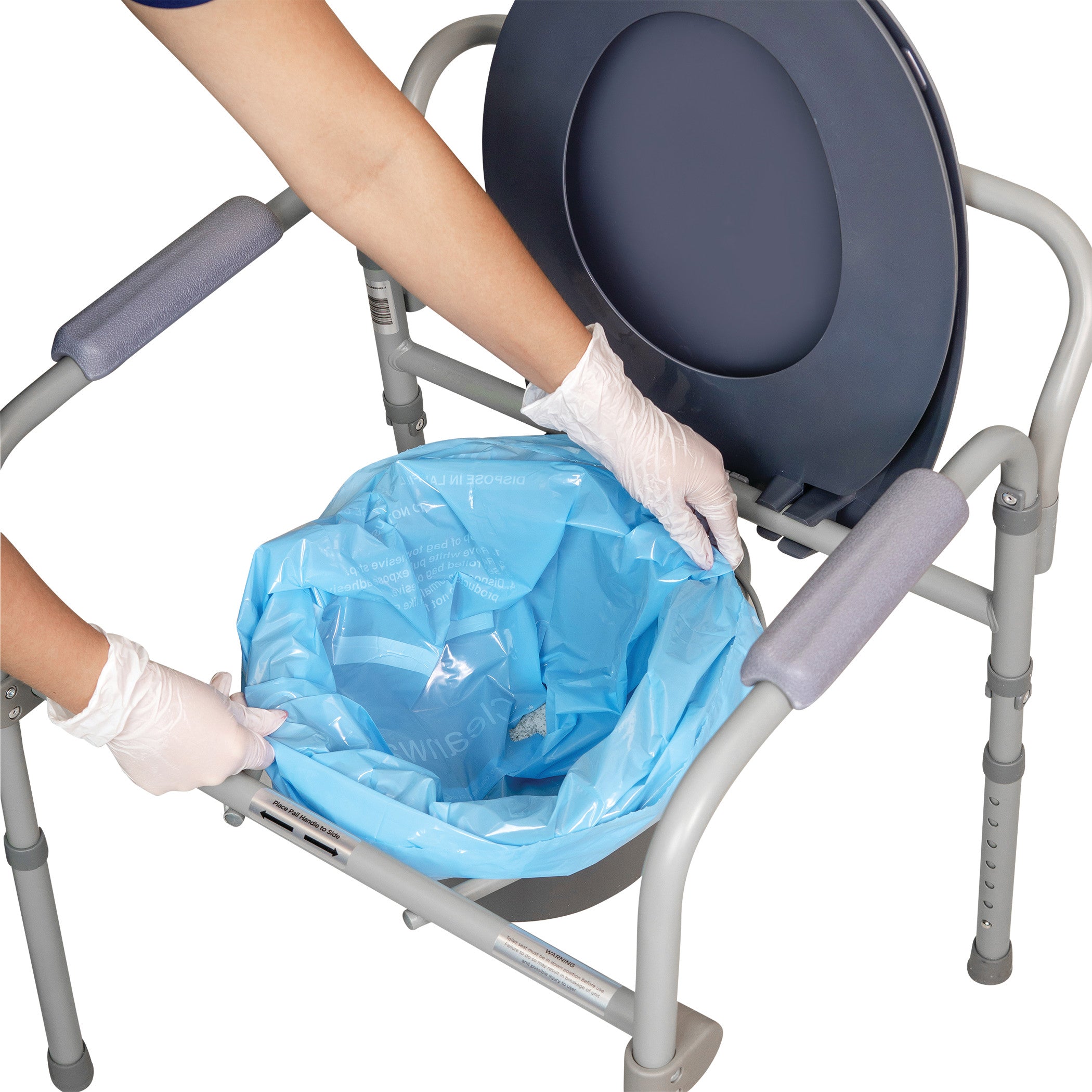 A person wearing gloves is placing a blue THE SANI-BAG+ Commode Liner in a portable commode chair.