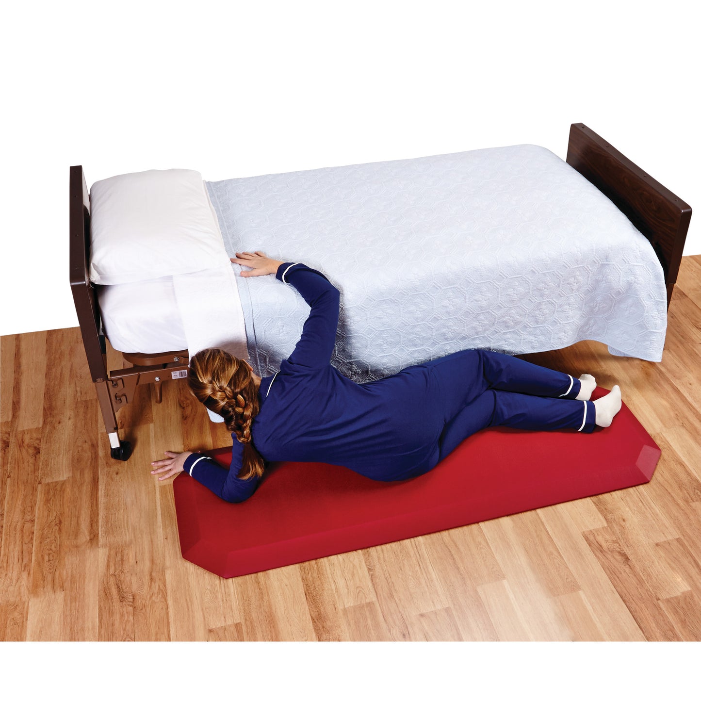A person lies next to a bed on a Trip-Resistant Bedside Fall Mat, which is red and placed on a wooden floor.