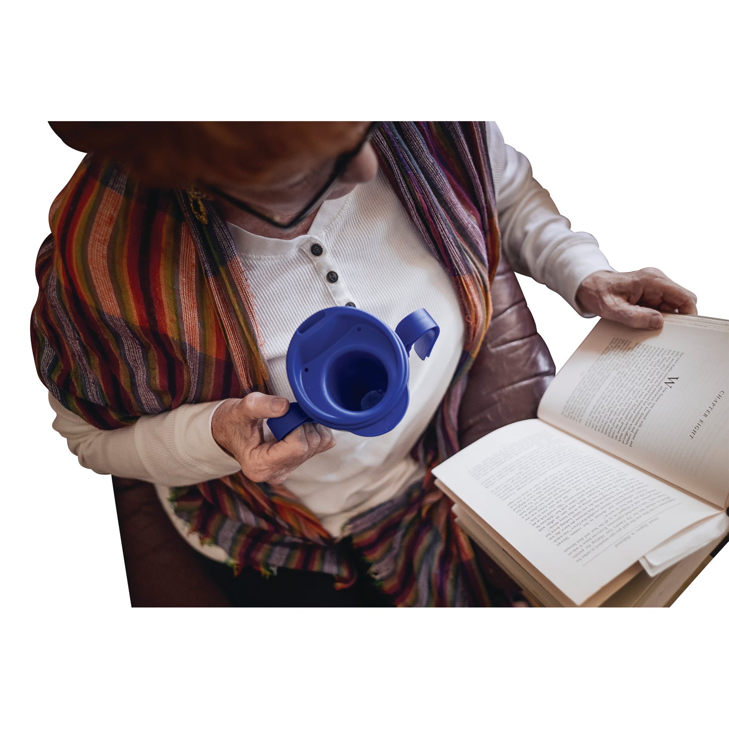 Person reading and holding a blue Provale Cup designed for controlled sips. The person wears a striped shawl and white shirt.