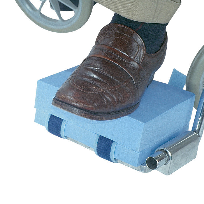 The AliMed Footrest Elevation Kit features a blue foam block elevating a foot in a brown shoe on a wheelchair footrest.