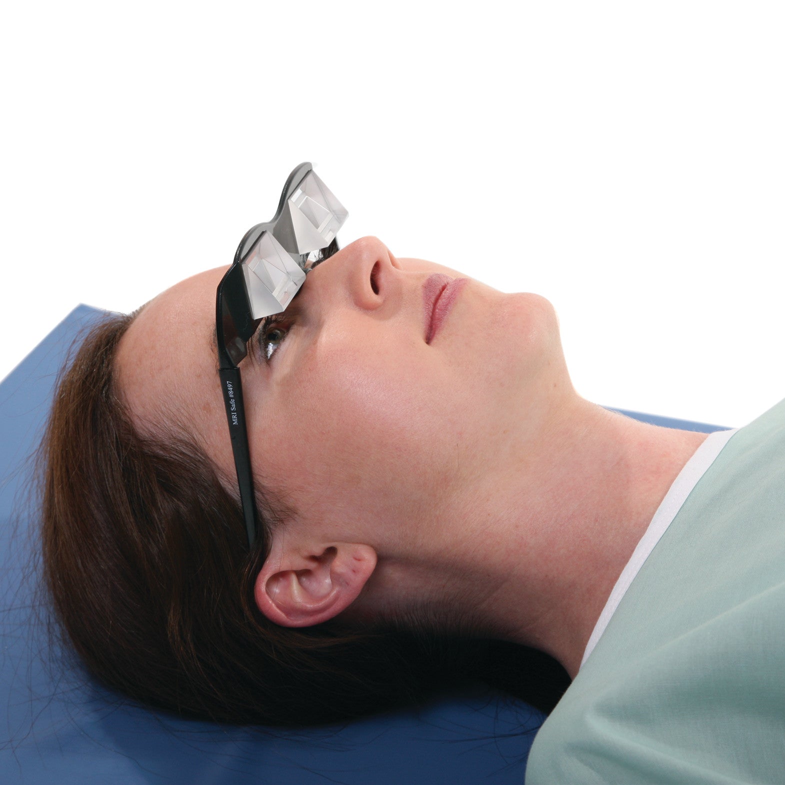 A person lies on their back wearing AliMed Deluxe Prism Glasses, which have angled prisms for reading or viewing while reclined.