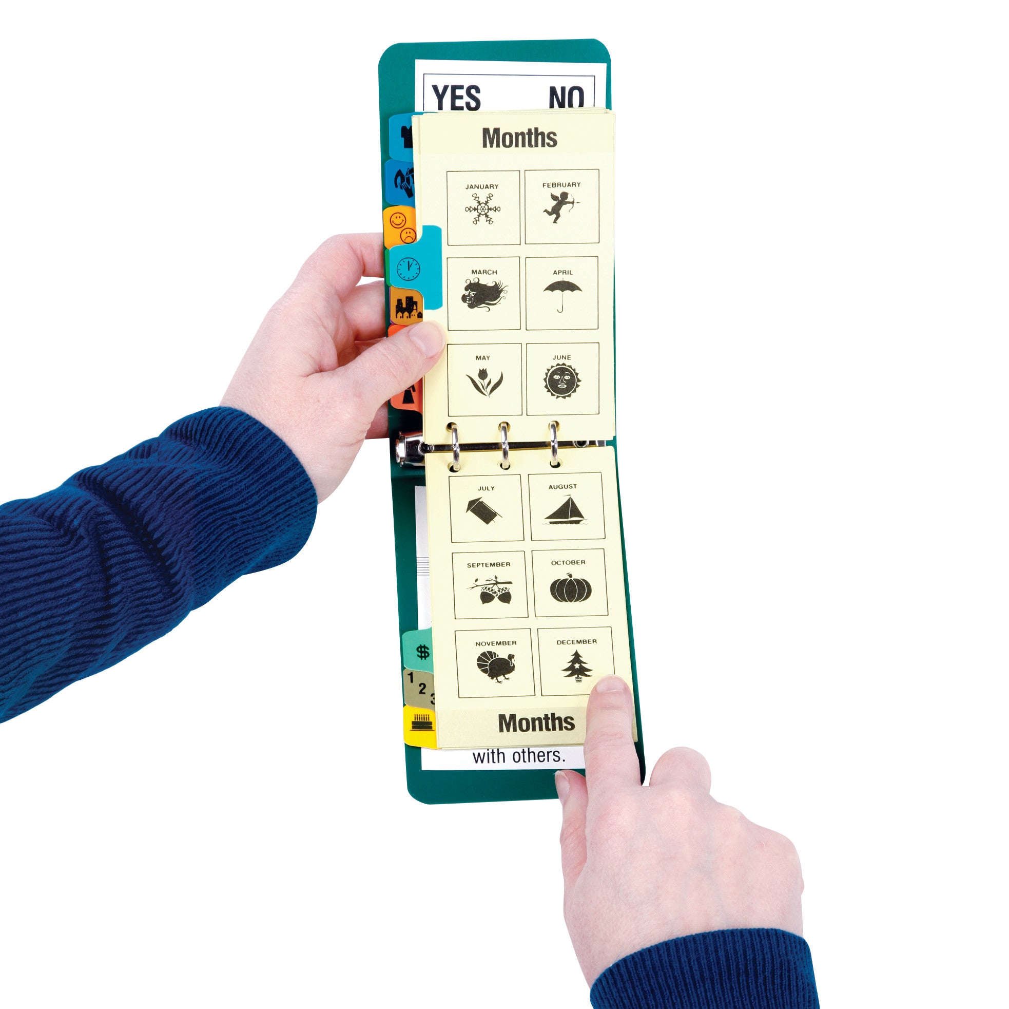Hands hold an AliMed Picture Communicator, showing a page with months and icons like a snowflake and leaf. Tabs are visible.