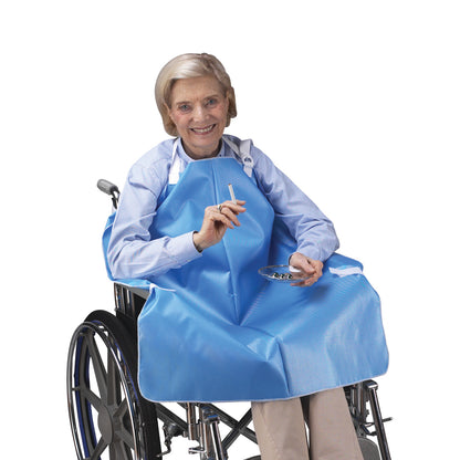 An elderly person sits in a wheelchair wearing a blue SkiL-Care Wheelchair Smoker's Apron, holding a cigarette with an ashtray.